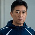 一位中年男性，穿着运动外套，表情认真
